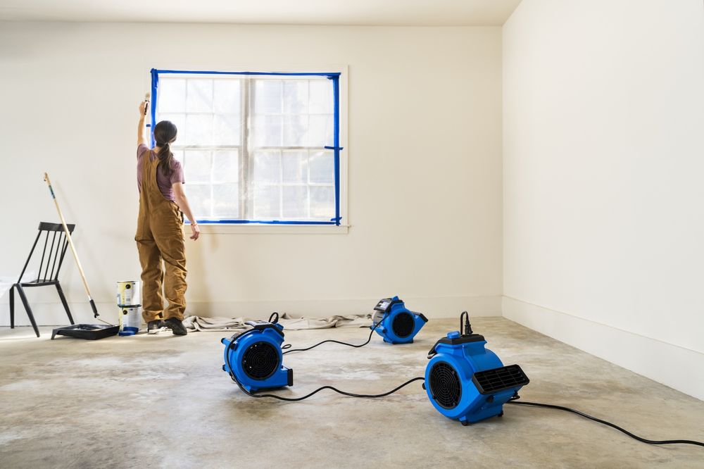 Professional air movers and dehumidifier drying a water damaged room